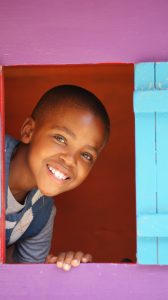 young boy smiling from the window of a playhouse