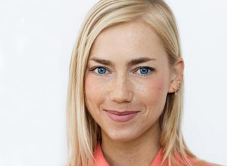 Laura Smiling With Blue Eyes And Fair Hair, Wearing A Coral Top In A Professional Headshot Against A Light Background